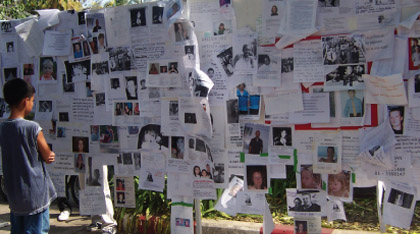 A child looks intently at the notice board in Phuket's City Hall where pictures of missing loved ones are put up by their next-of-kin.